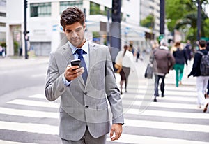 The modern multitasking man. A cropped shot of a handsome young businessman texting while walking in the city.