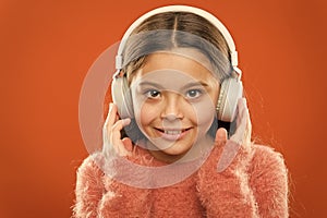 Modern music is her life style and pleasure. Little modern girl wearing bluetooth headphones. Small child listening to