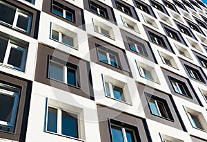 Modern and new apartment building. Photo of a tall block of flats with balconies against a blue sky.