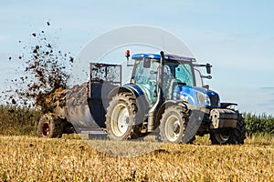 Modern New Holland tractor Tractor spreading manure on fields