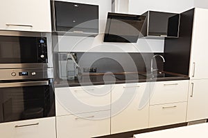 Modern new light interior of kitchen with white and black furniture