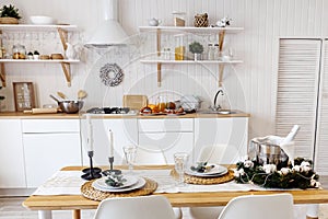 Modern new light interior of kitchen with white furniture and dining table