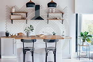 Modern new light interior of kitchen with white furniture and dining table.