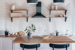 Modern new light interior of kitchen with white furniture and dining table.