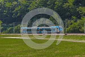 Modern and new passenger swiss made Train in white and blue color is traveling on a dual track railway line in the rural setting photo