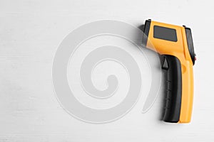 Modern non-contact infrared thermometer on wooden background, top view. Space for text