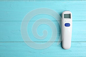 Modern non contact thermometer on blue wooden table, top view. Space for text