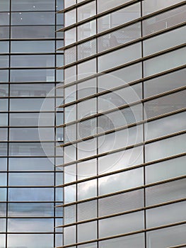 Modern office architecture abstract with geometric shapes of tall buildings reflecting the blue cloudy sky in large