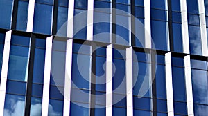 Modern office building detail, glass surface on a clear sky background.