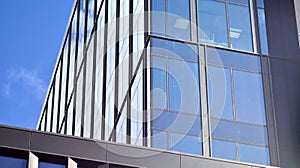 Modern office building detail, glass surface on a clear sky background.