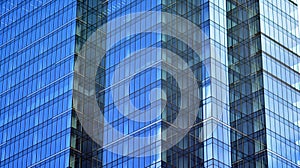 Modern office building detail, glass surface on a clear sky background.