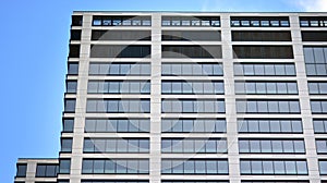 Modern office building detail, glass surface on a clear sky background.