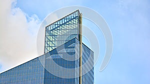 Modern office building detail, glass surface on a clear sky background.