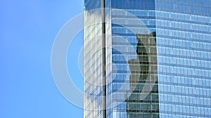 Modern office building detail, glass surface on a clear sky background.