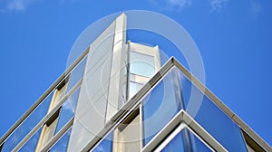 Modern office building detail, glass surface on a clear sky background.