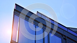 Modern office building detail, glass surface on a clear sky background.