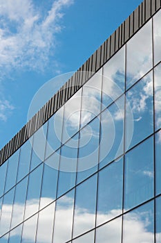 Modern office building exterior with glass facade on clear sky background. Transparent glass wall of office building