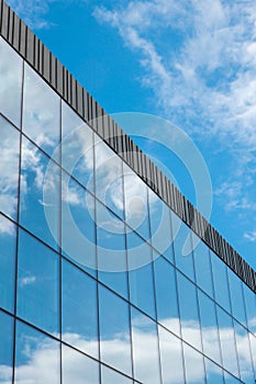 Modern office building exterior with glass facade on clear sky background. Transparent glass wall of office building