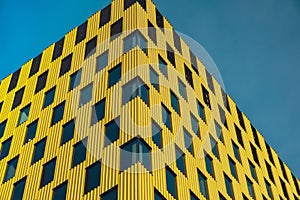 Modern office building exterior with glass facade on clear sky background. Transparent glass wall of office building