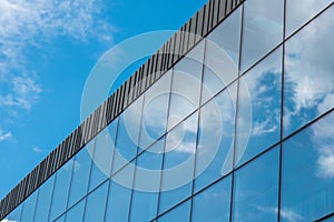 Modern office building exterior with glass facade on clear sky background. Transparent glass wall of office building