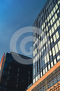 Modern office building exterior with glass facade on clear sky background. Transparent glass wall of office building