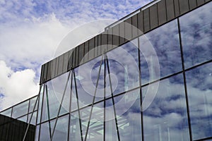 Modern office building exterior with glass facade on clear sky background. Transparent glass wall of office building