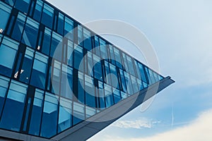 Modern office building exterior with glass facade on clear sky background. Transparent glass wall of office building