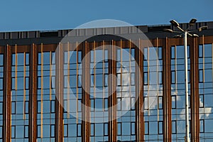 Modern office building exterior with glass facade on clear sky background. Transparent glass wall of office building