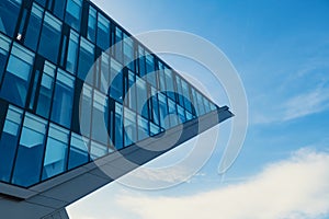 Modern office building exterior with glass facade on clear sky background. Transparent glass wall of office building