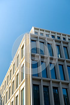 Modern office building exterior with glass facade on clear sky background. Transparent glass wall of office building