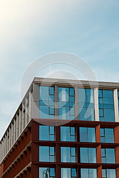 Modern office building exterior with glass facade on clear sky background. Transparent glass wall of office building