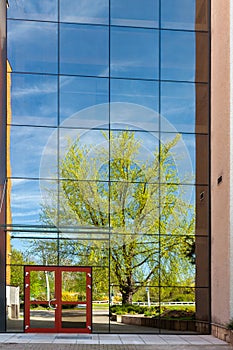 A modern office building with glass doors and windows, reflection in the glass of a city park Pardubice