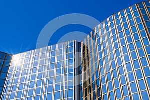 Modern office building with glass facade in front of blue sky