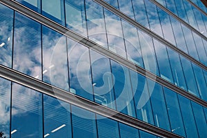 Modern office building glass facade, sky reflection in the windows of skyscraper