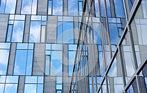 Modern office building with glass walls reflecting blue sky
