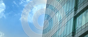 Modern office building with reflection of blue sky and clouds on its windows