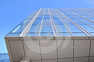 Modern office building wall made of steel and glass with blue sky