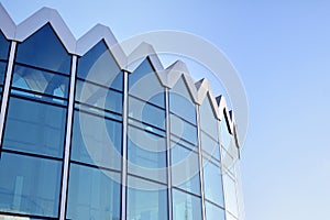 Modern office building wall made of steel and glass with blue sky