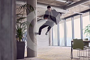 In the modern office, a businessman with a briefcase captivates everyone as he performs thrilling aerial acrobatics