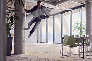 In the modern office, a businessman with a briefcase captivates everyone as he performs thrilling aerial acrobatics