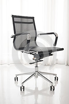 Modern office chair in white room interior parquet wood floor.Wooden table with laptop and chair in office