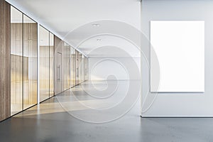 Modern office corridor with a blank white framed poster mockup on a wall, glass partitions and wooden doors, concept of