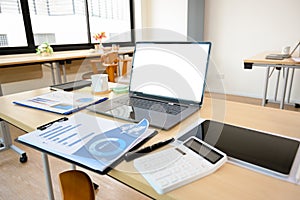 Modern office desk with open laptop computer, report, calculator and supplies