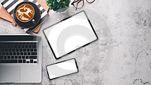 Modern office desk workplace with blank screen digital tablet and smartphone, laptop, eyeglass, notebook and cup of coffee