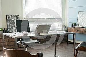 Modern office interior design with office chair and desk in front of windows. Workplace