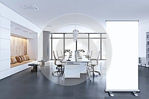 A modern office interior with desks, chairs, and a lounge area against large windows overlooking a cityscape, light and spacious.