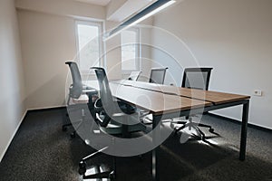 Modern office interior with empty chairs and a large conference table under natural light