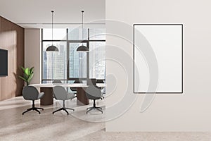 Modern office interior with a meeting area, large windows, and an empty poster on the wall, light tones, concept of corporate