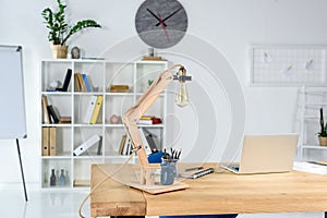 Modern office interior with wooden table, desklamp and stationery placed photo