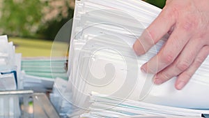 Modern office and overworking concept - male hands take a close-up of a huge sheaf of papers.